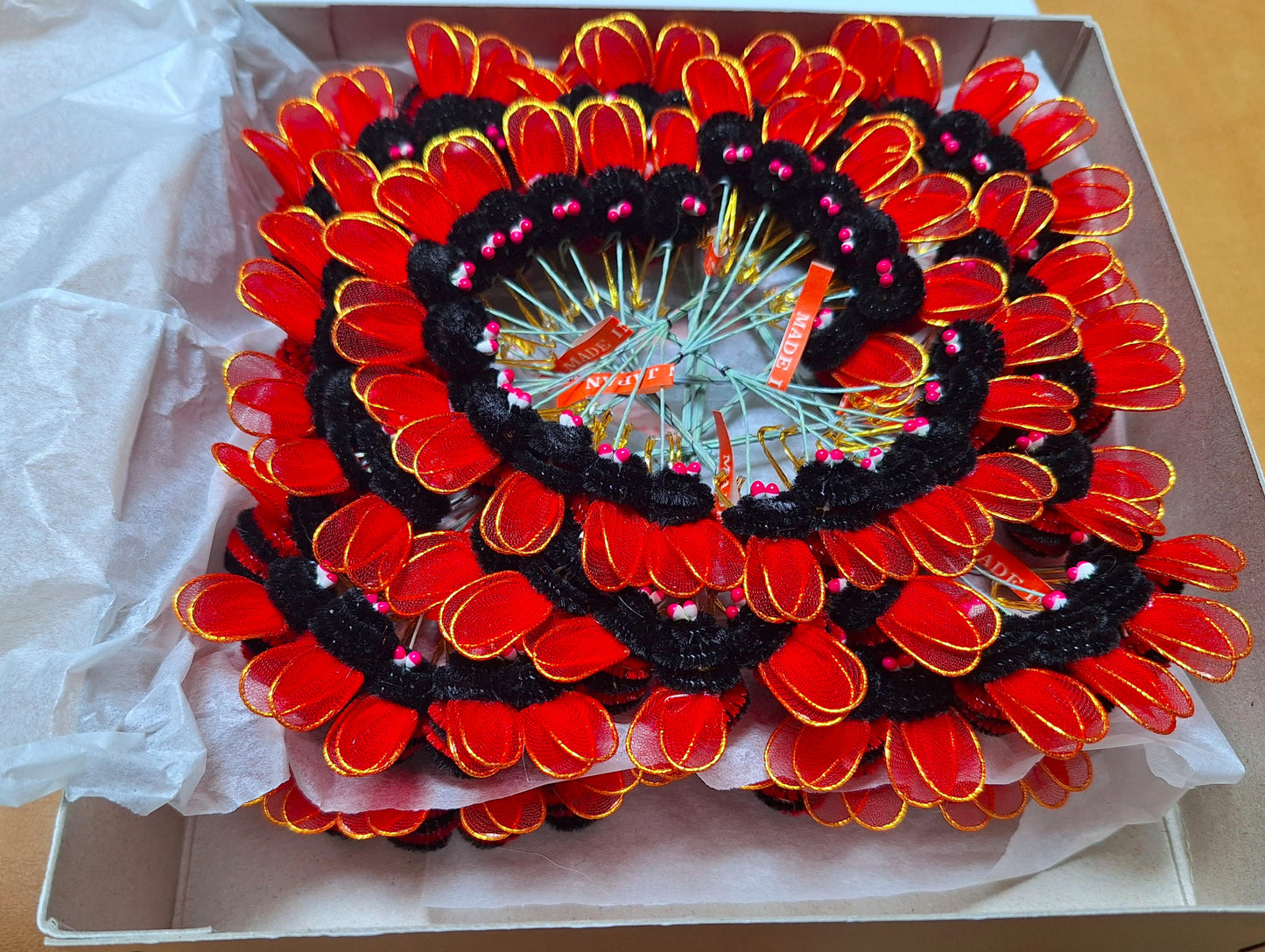 Red and black chenille bees on wire with nylon wings and pep eyes, tied in bunches of 6 and 24 groups of 6 artfully arranged in a spiral.