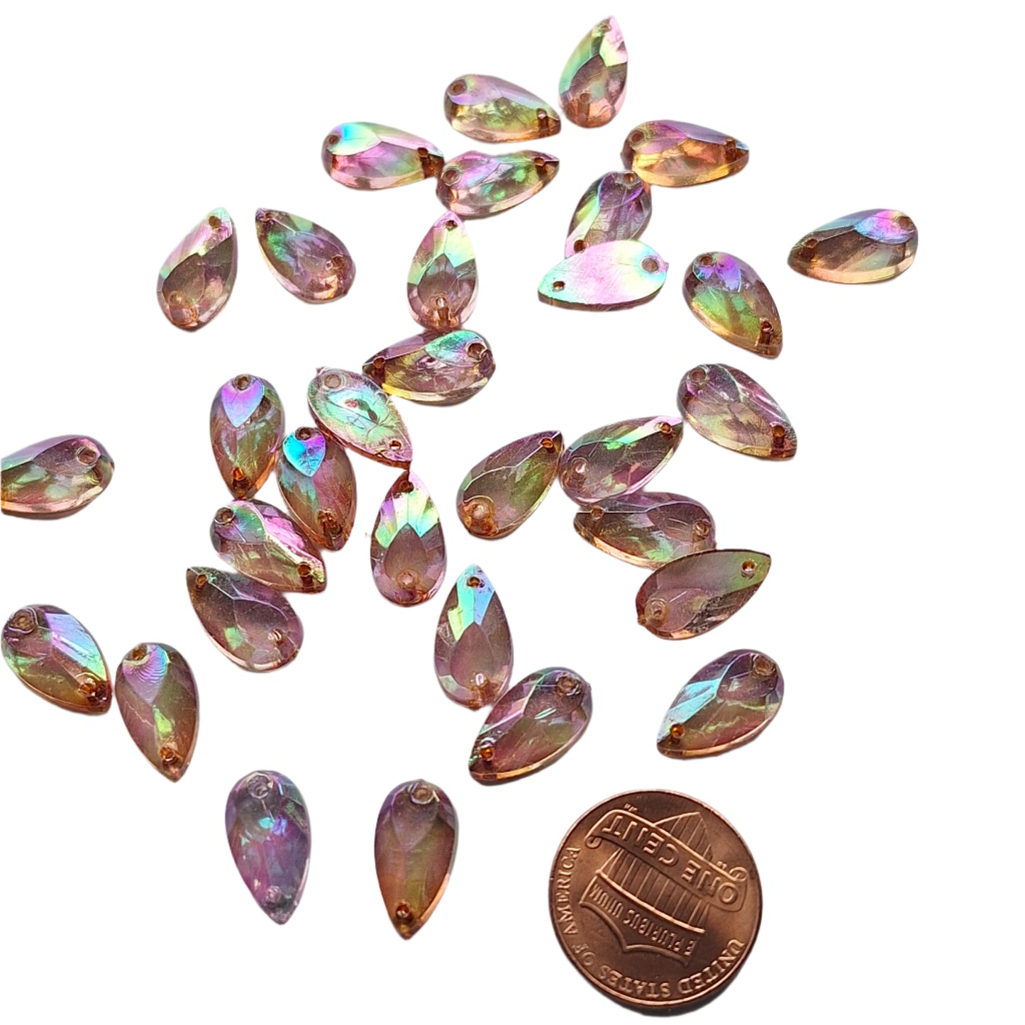 Amethyst AB teardrop cabochons shown in a group, including one flipped to display the sew-on back, with a penny for scale.
