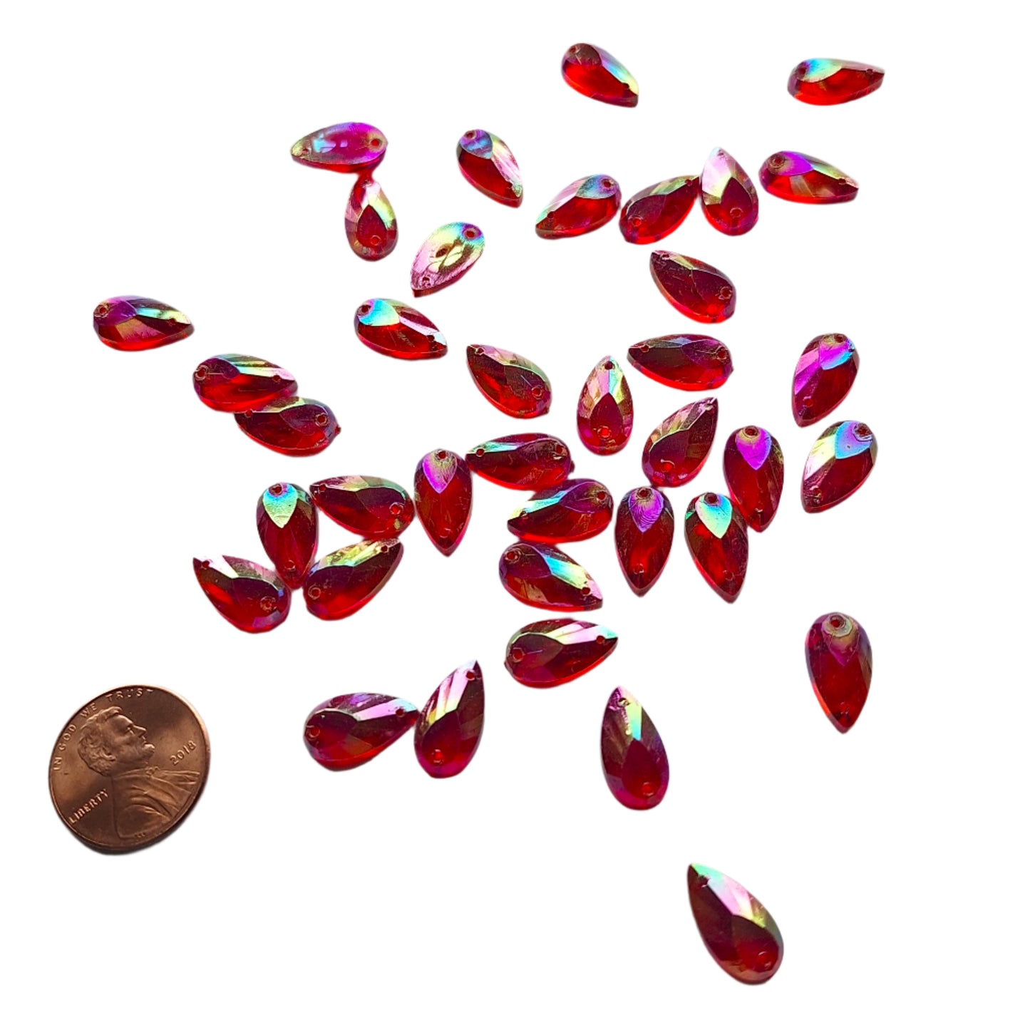 Ruby AB teardrop cabochons shown in a group, including one flipped to display the sew-on back, with a penny for scale.