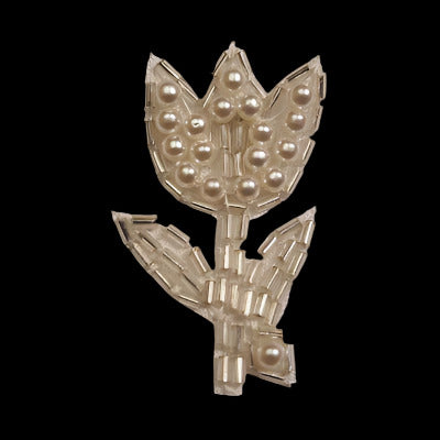 Tulip-shaped applique with an outline of bugle beads and imitation pearls covering each region, on a black background
