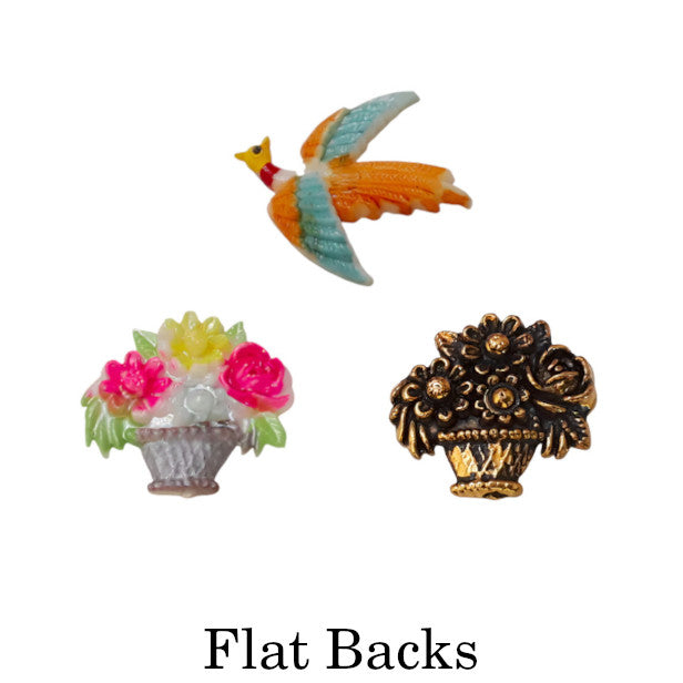 Collage of vintage plastic flat backs including a hand-painted bird in flight, a floral basket motif, and a metalized floral ornament, representing the Flat Backs collection.