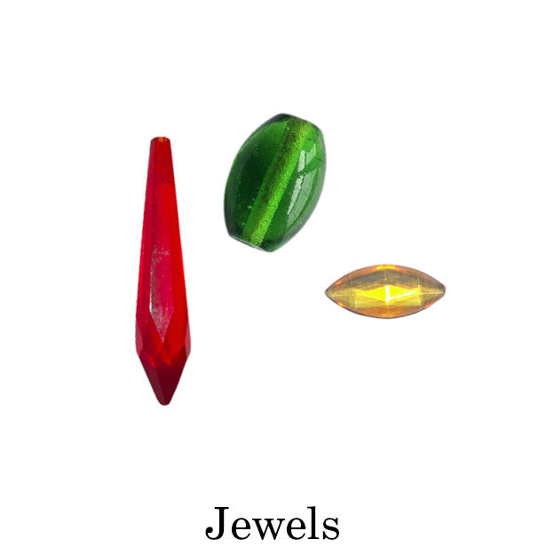 Assorted vintage decorative jewels in faceted and smooth forms, shown in red, green, and amber tones