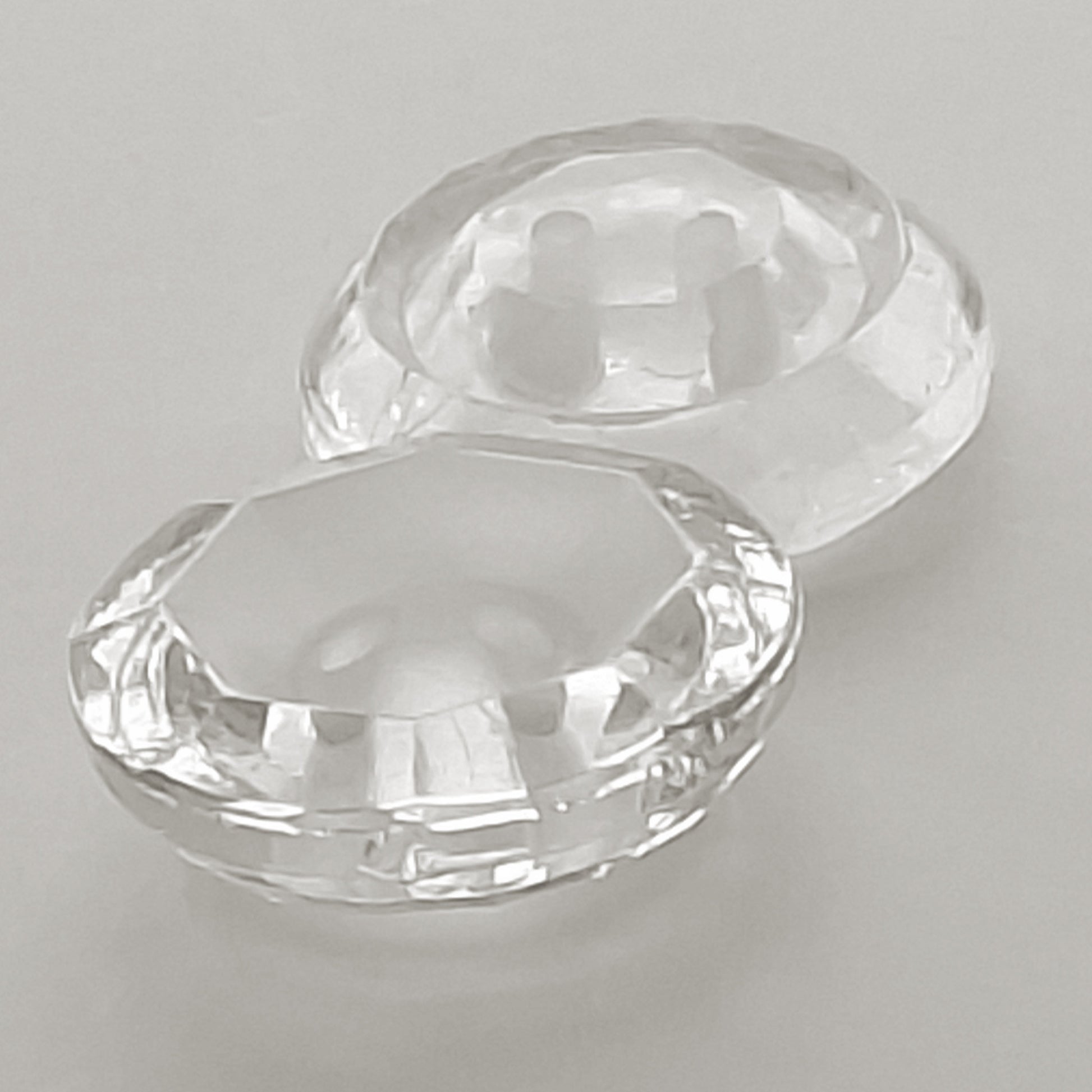Side view of two clear glass buttons with frosted centers, one positioned right-side up and the other facing down, showing the thickness and outer shape of the rim.