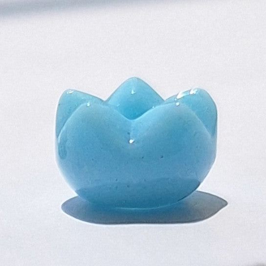 Turquoise glass spacer bead with a tulip-style cut surface over a rounded body, viewed from the side.