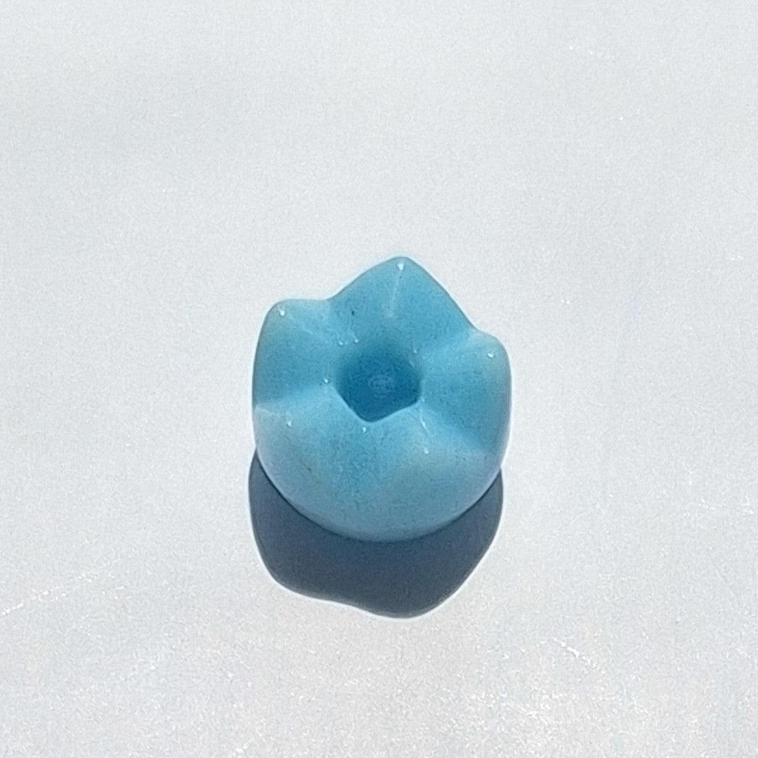 Turquoise glass spacer bead with a tulip-style cut surface over a rounded body, viewed from above.