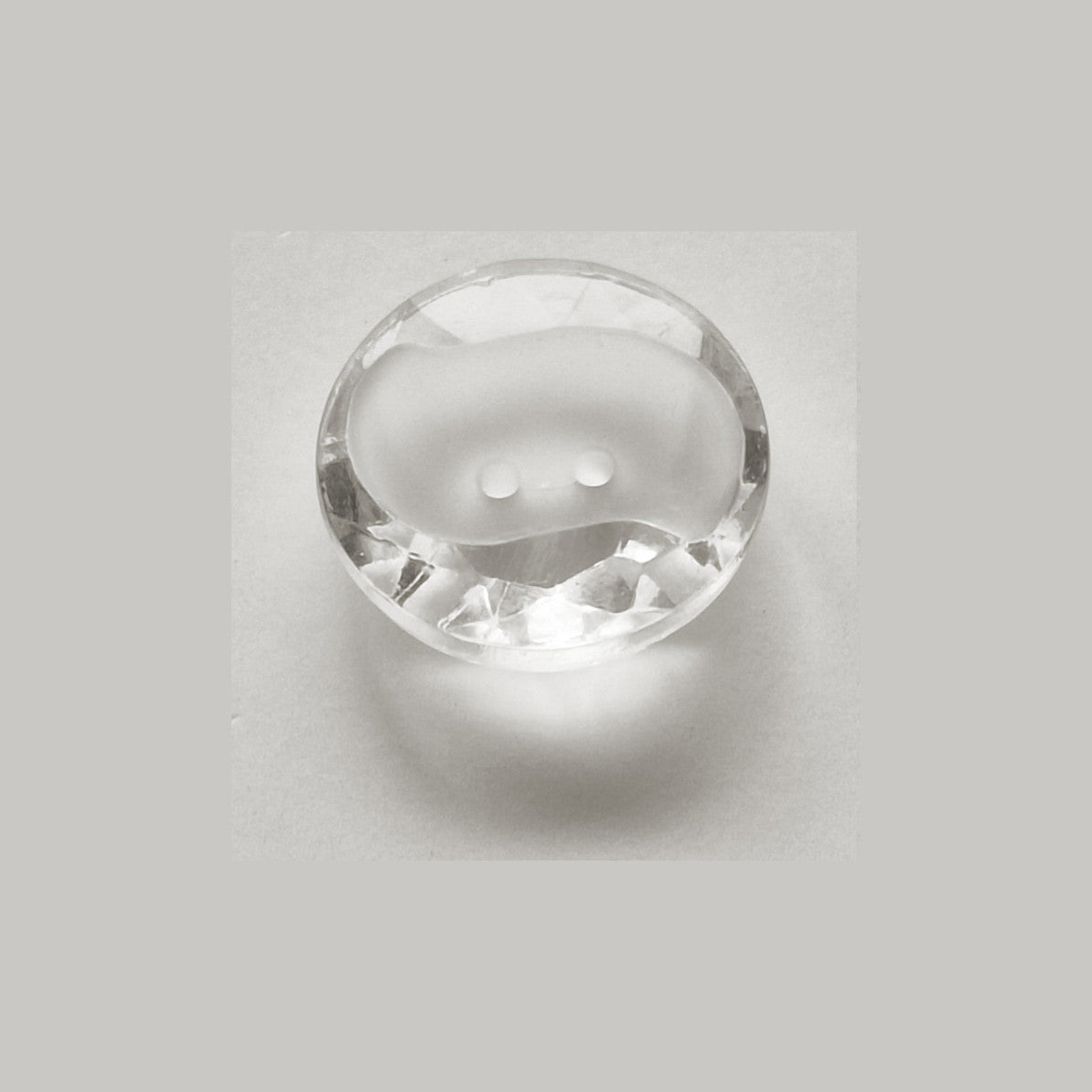 Clear crystal glass button with a frosted S-shaped center recess and two-hole attachment in 11.4mm size.