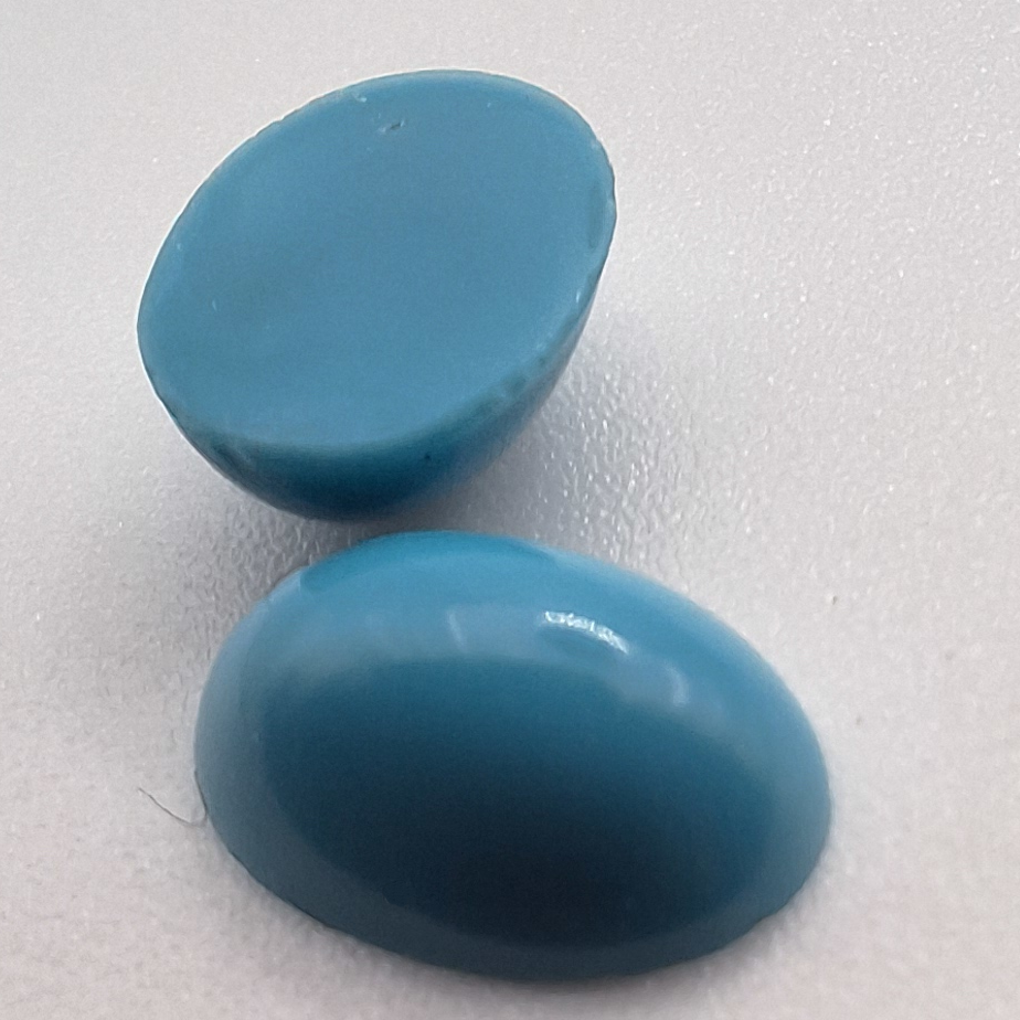 Front and back of a turquoise 10×7 mm oval imitation-turquoise glass cabochon with a polished back on a neutral background.