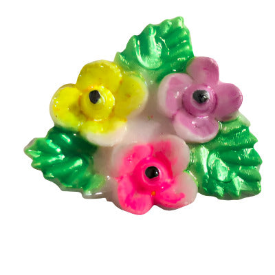 Hand-painted plastic flat back of a trio of flowers and green leaves.