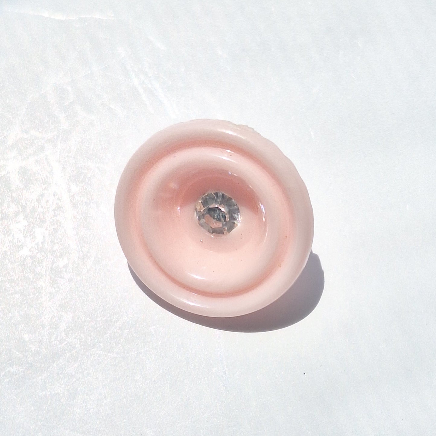 Pink plastic cup-shaped shank button with clear glass rhinestone center, 18mm.