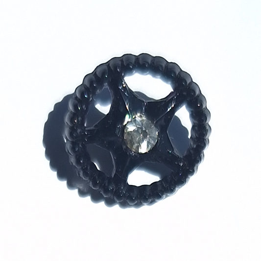Black star-in-wheel plastic button with openwork rim and central glass rhinestone, 14mm.