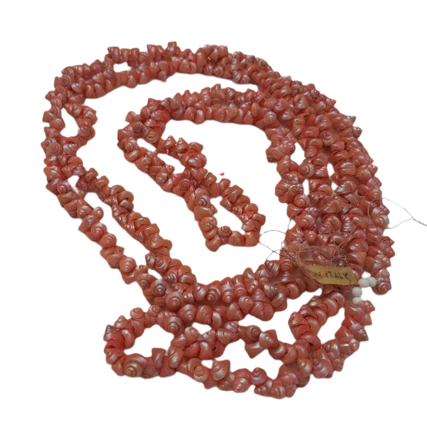 Light pink strung seashells with hand-punched holes and natural 1/4-inch shells shown on complete strand with made-in-italy label.