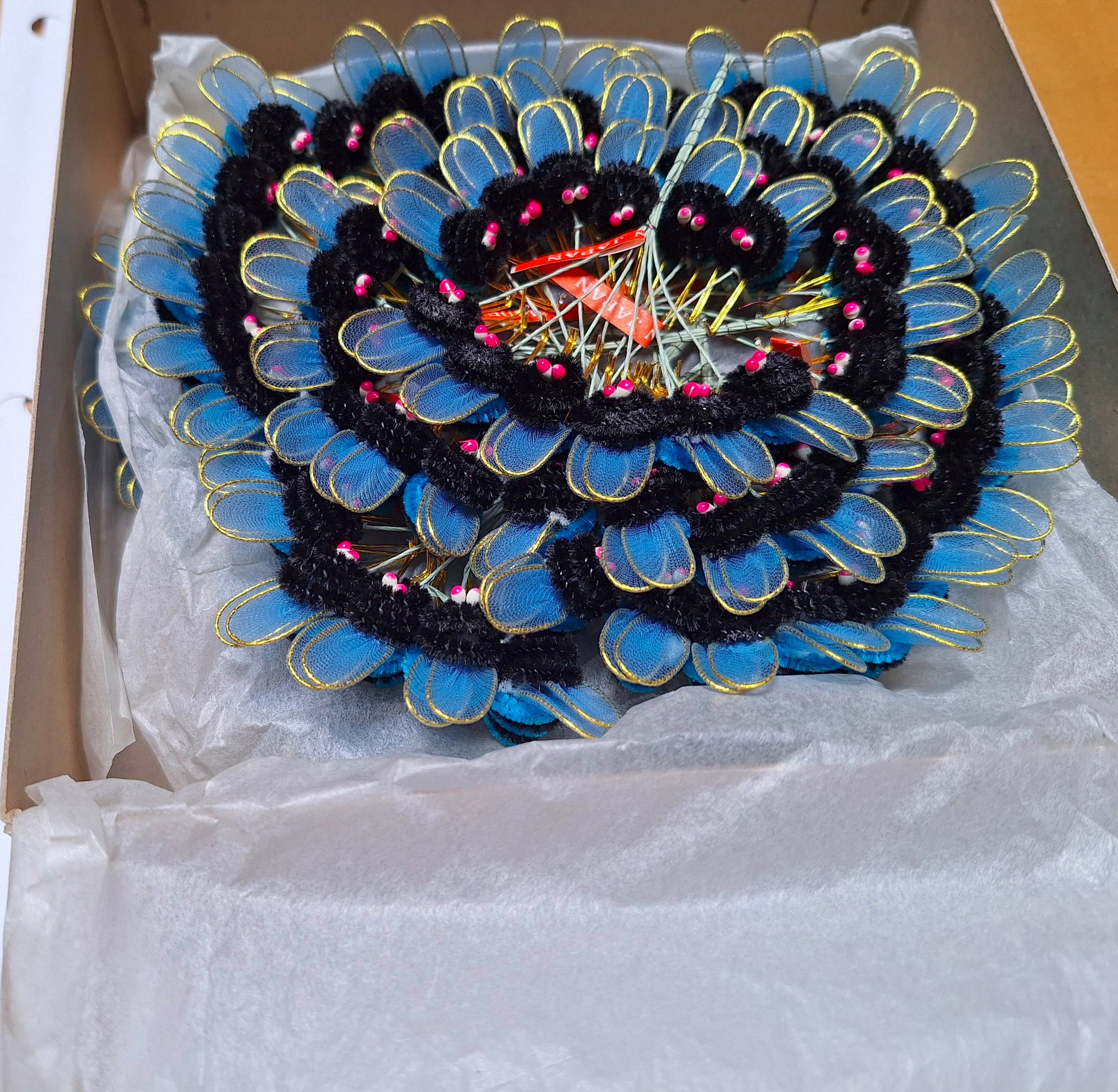 Blue and black chenille bees on wire with nylon wings and pep eyes, tied in bunches of 6 and 24 groups of 6 artfully arranged in a spiral.