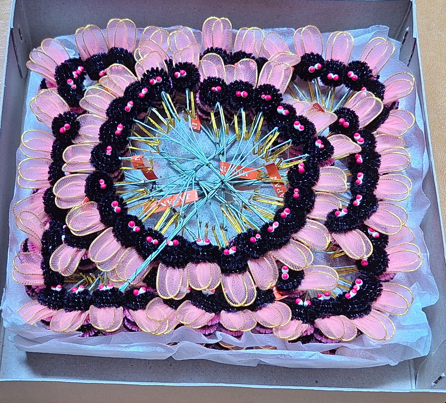 Pink and black chenille bees on wire with nylon wings and pep eyes, tied in bunches of 6 and 24 groups of 6 artfully arranged in a spiral.