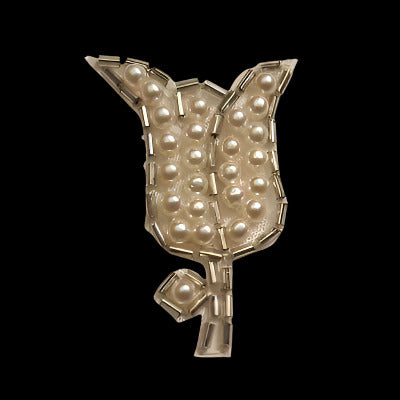 Tulip-shaped applique with an outline of bugle beads and imitation pearls covering each region, on a black background