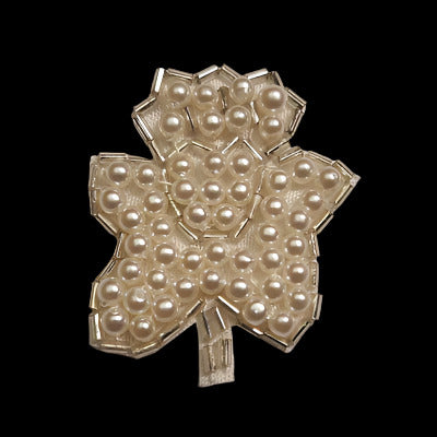 Leaf-shaped applique with an outline of bugle beads and imitation pearls covering each region, on a black background
