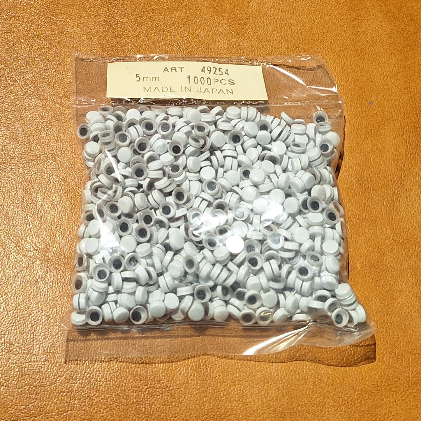 Bag of 1000 5mm paste-on googly eyes with a flat black pupil made in Japan.