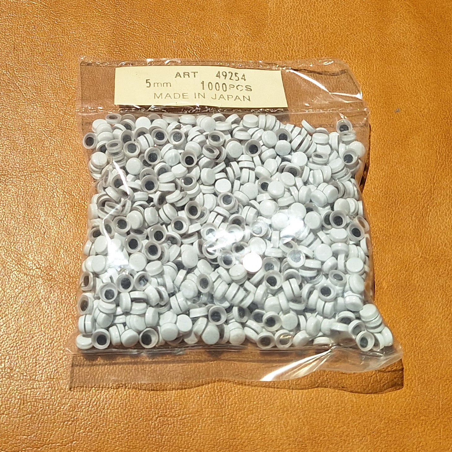 Bag of 1000 5mm paste-on googly eyes with a flat black pupil made in Japan.