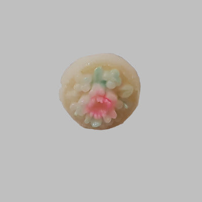 Small cream button with a raised hand-painted floral motif in pink and green, shown from the front to display the detailed design.