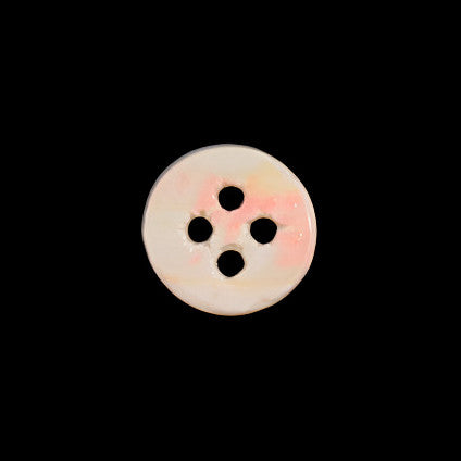 Back view of a troca shell button showing natural shell coloration and the four-hole structure on a dark background.