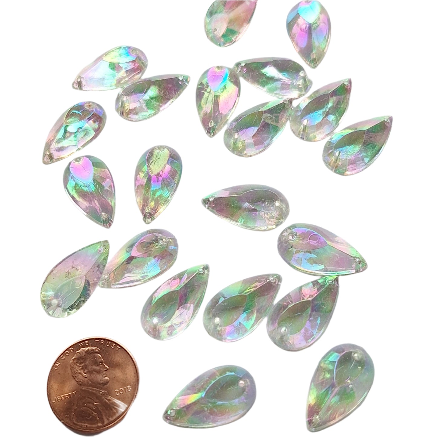 Crystal AB teardrop cabochons shown in a group, to display the sew-on back, with a penny for scale.