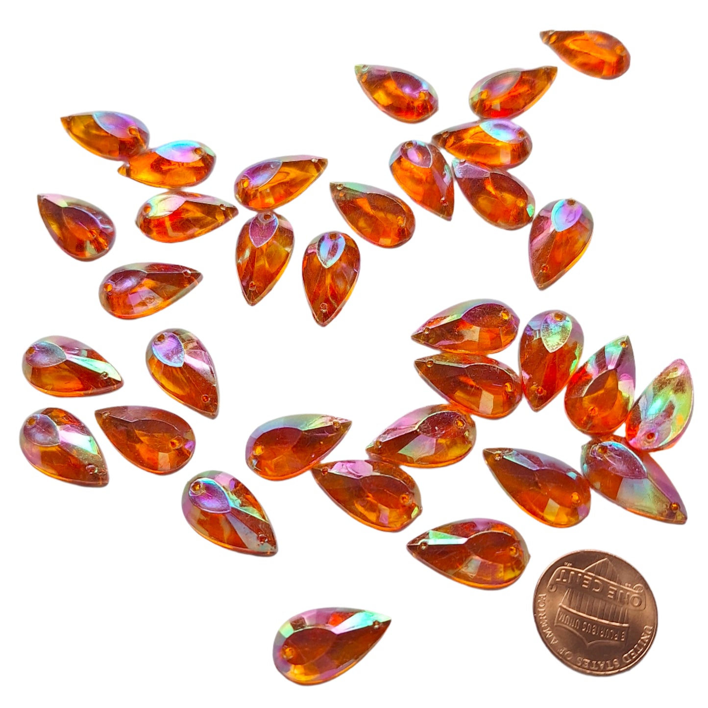 Topaz AB teardrop cabochons shown in a group, including one flipped to display the sew-on back, with a penny for scale.