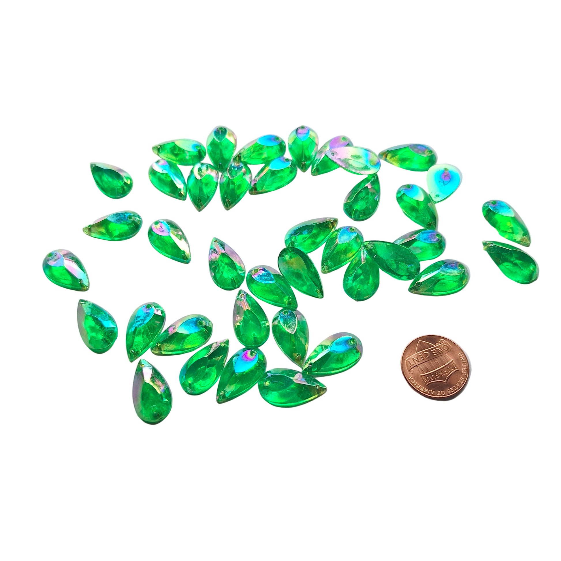 Emerald AB teardrop cabochons shown in a group, including one flipped to display the sew-on back, with a penny for scale.