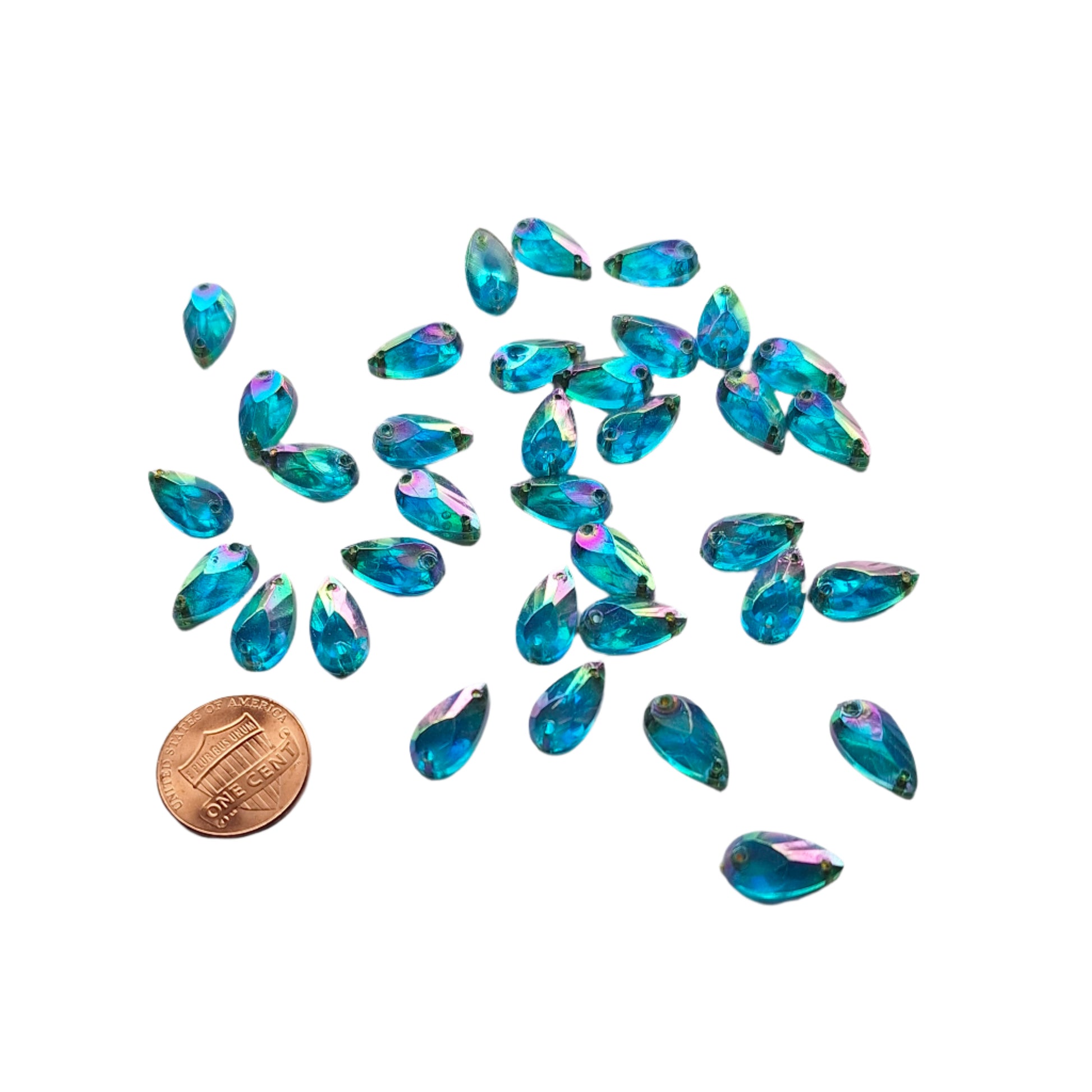 Sapphire AB teardrop cabochons shown in a group, including one flipped to display the sew-on back, with a penny for scale.