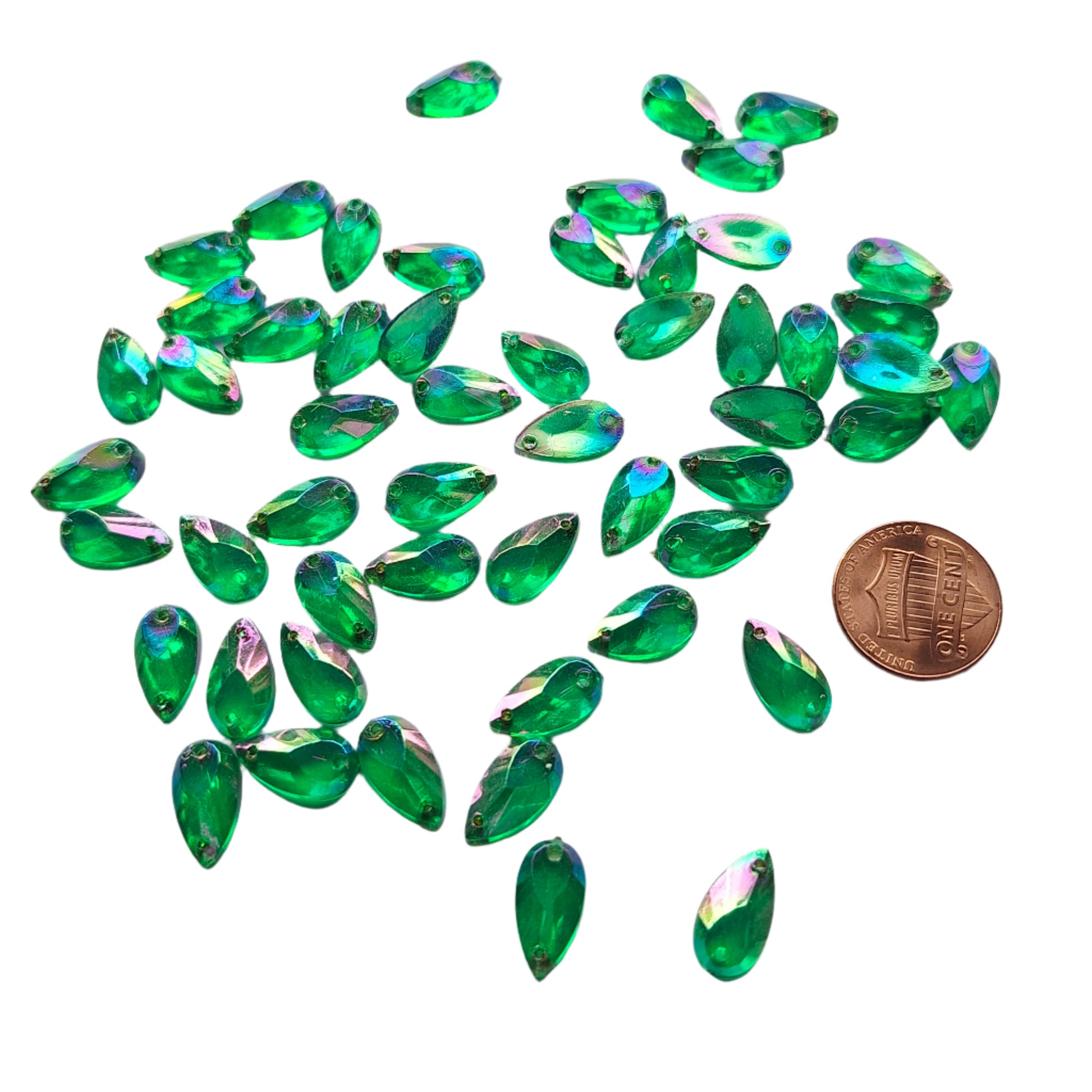 Emerald AB teardrop cabochons shown in a group, including one flipped to display the sew-on back, with a penny for scale.