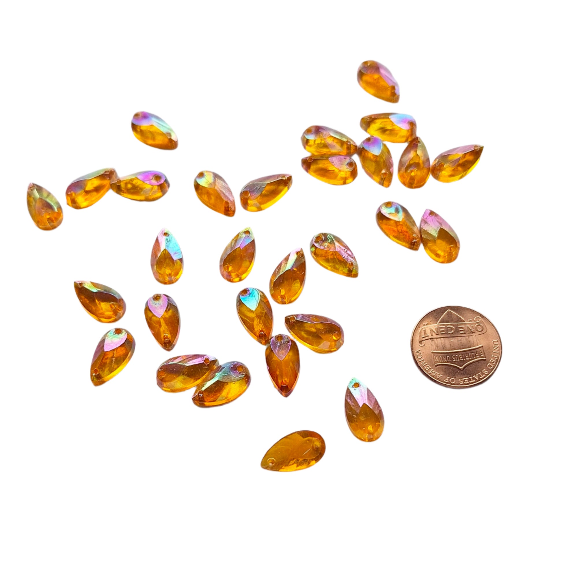 Topaz AB teardrop cabochons shown in a group, including one flipped to display the sew-on back, with a penny for scale.