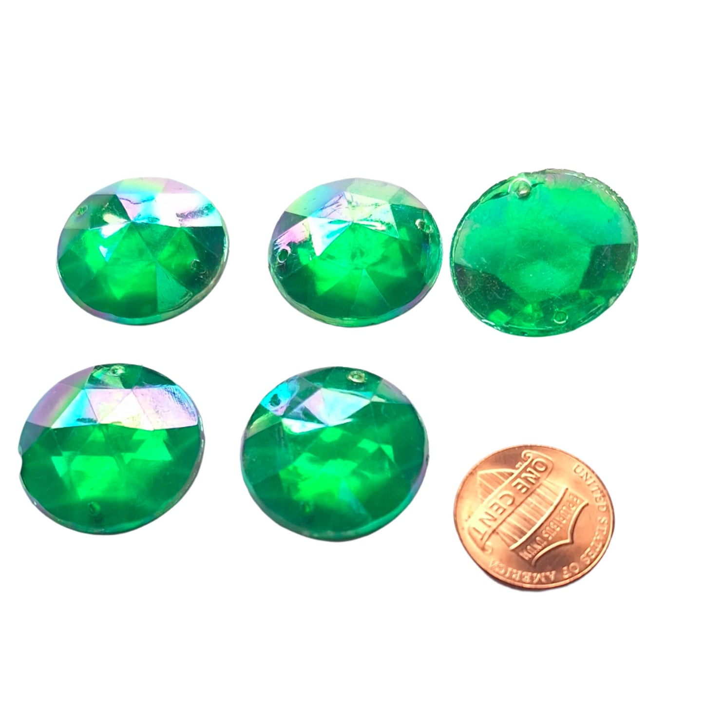 Emerald AB round faceted plastic cabochons arranged in a group of five, with one flipped to show the two-hole sew-on back; penny included for scale.