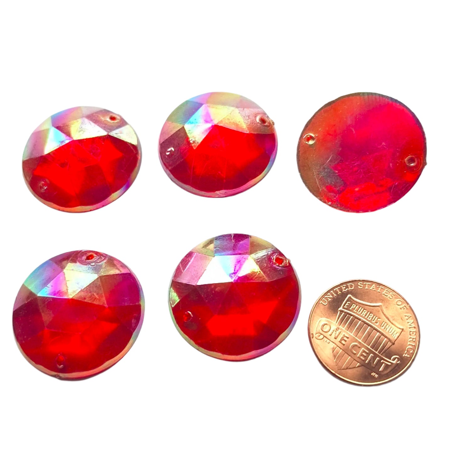 Ruby AB round faceted plastic cabochons arranged in a group of five, with one flipped to show the two-hole sew-on back; penny included for scale.