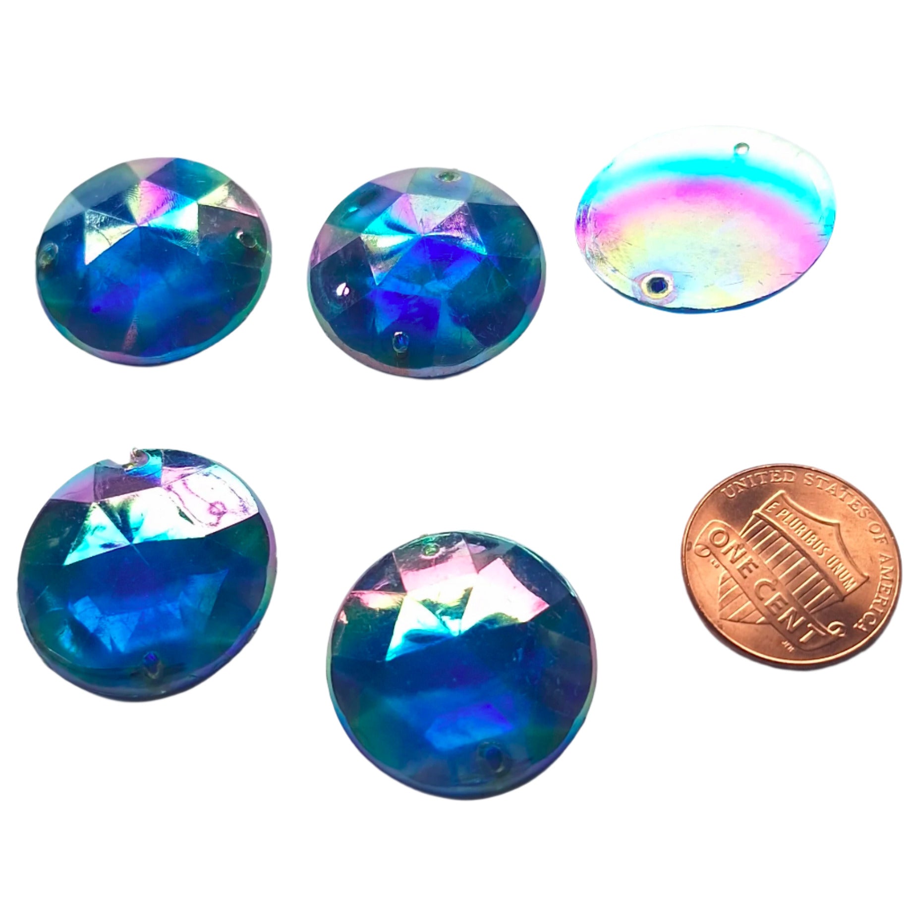 Sapphire AB round faceted plastic cabochons arranged in a group of five, with one flipped to show the two-hole sew-on back; penny included for scale.