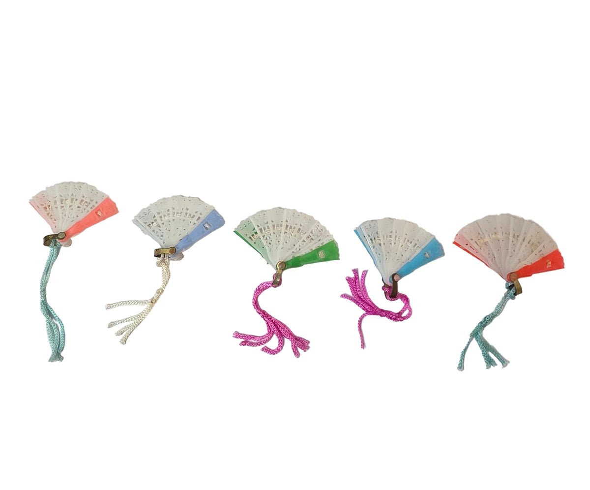 Five vintage miniature plastic folding fans shown open in pink, blue, green, aqua, and red, with decorative white center panels and assorted silk tassel colors.