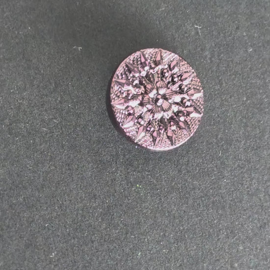 Rotating faceted purple mirrored button reflecting light against a dark background.