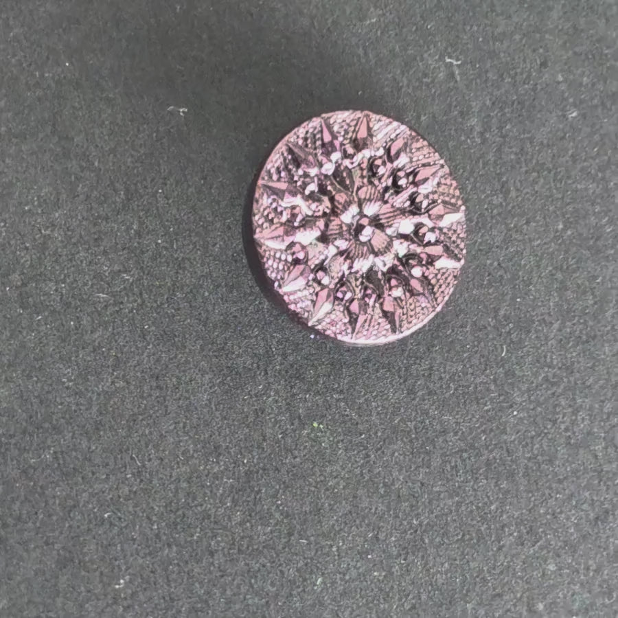 Rotating faceted purple mirrored button reflecting light against a dark background.