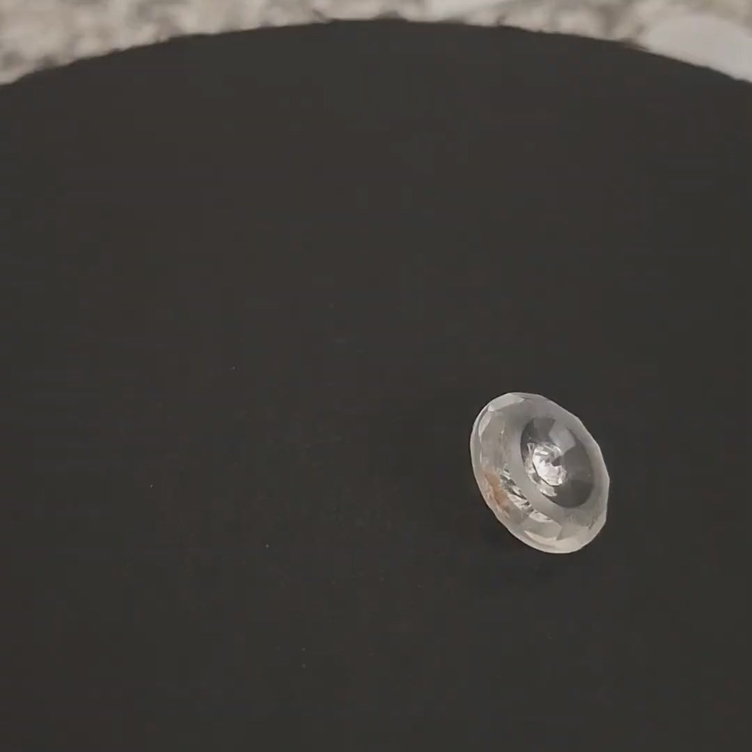 Crystal glass button with faceted rim front and back, frosted ring, clear inner field, and central rhinestone, shown rotating slightly on a turntable, shank back, 18mm size