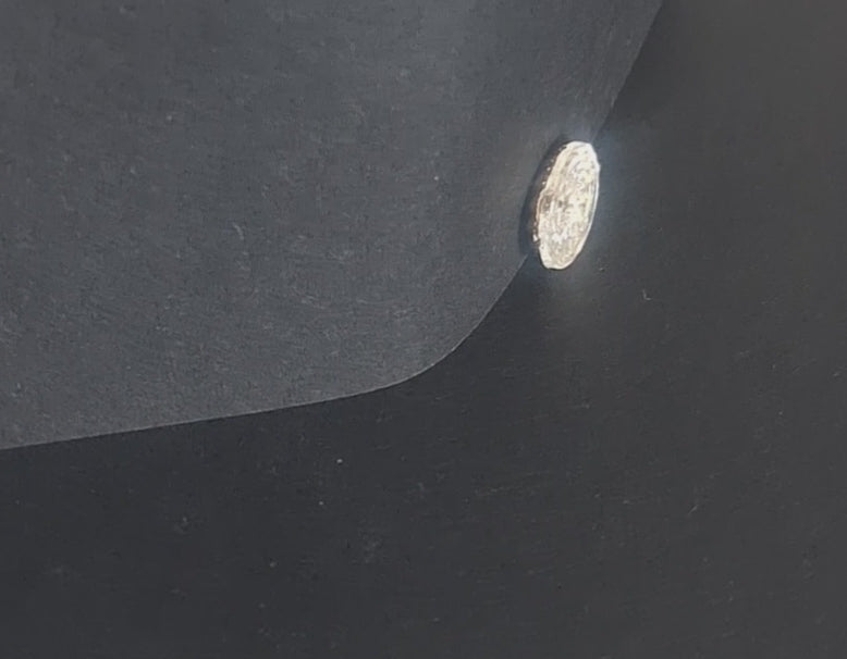 Mirrored glass button with concave form and faceted swirl pattern, two-hole, 14mm, shown in video with light movement to display the mirrored finish.